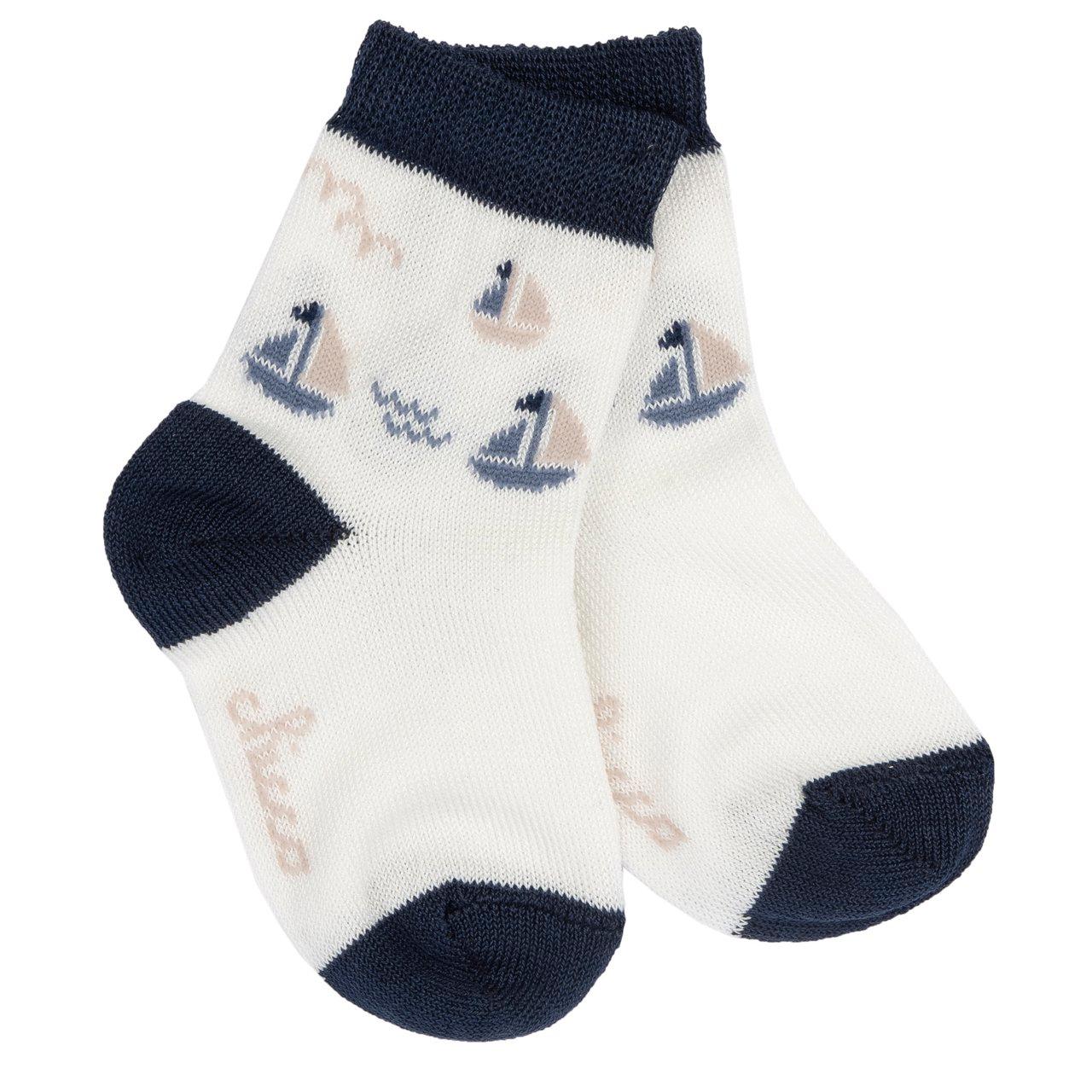 Calzini Chicco in cotone mercerizzato bianco per bambini, con fantasia jacquard di barchette e dettagli blu su polsino, punta e tallone, ideali per primavera/estate. | Chicco